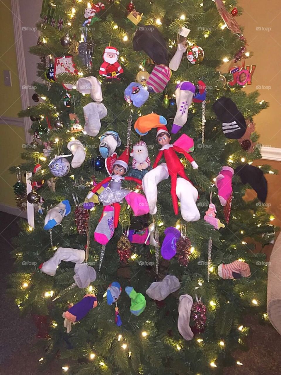 Elf on the Shelf decorated the Christmas tree with socks. 