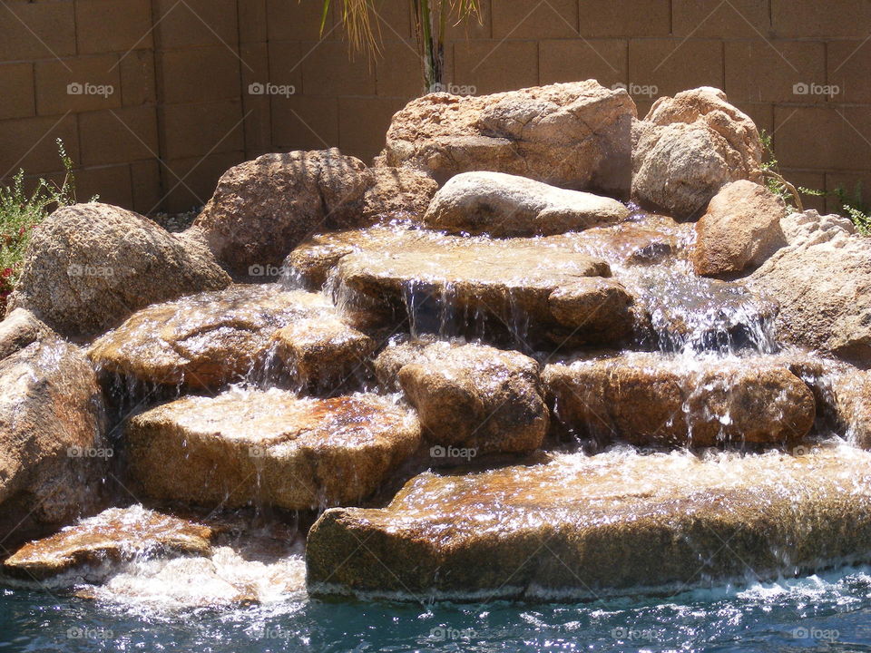 Waterfall next to an inground pool