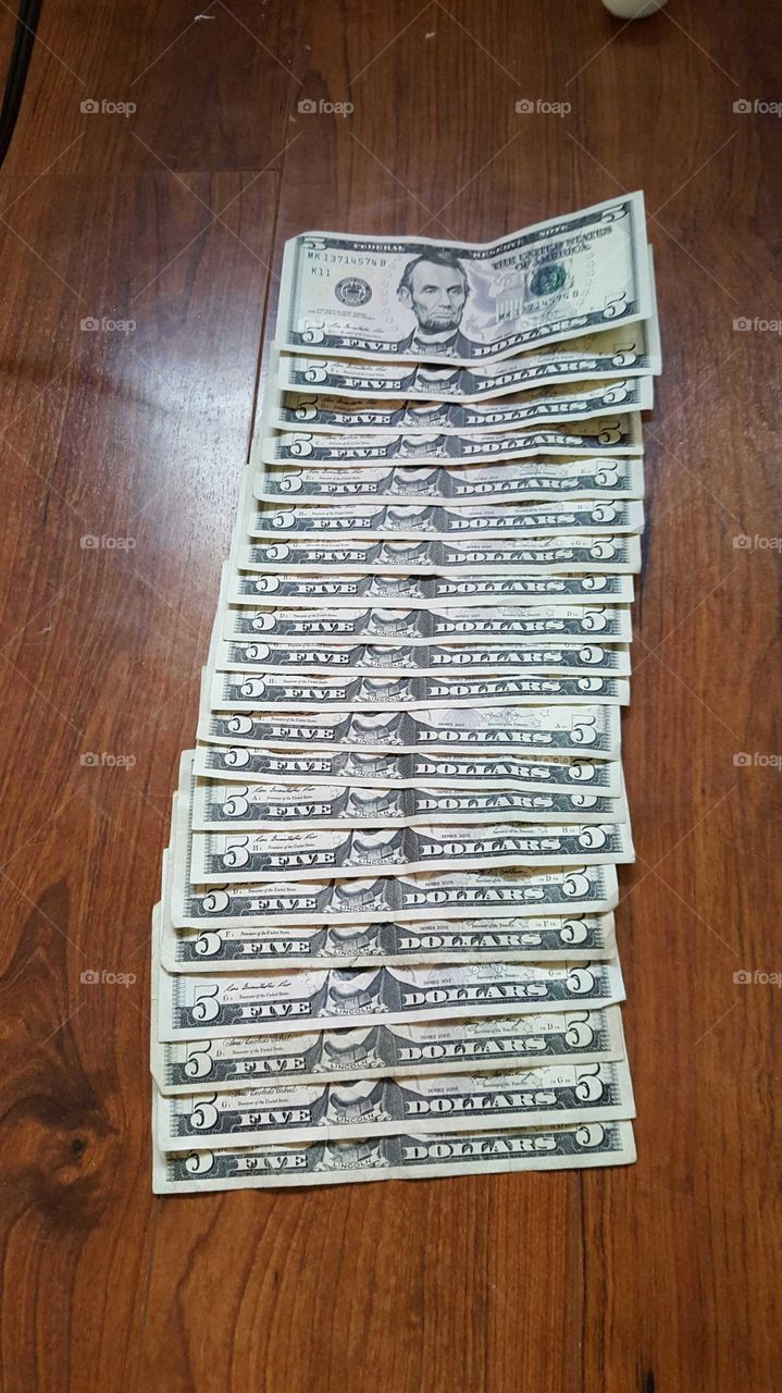 Five dollars bills on wooden table.