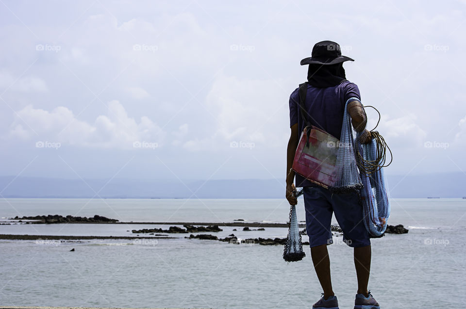 Man holding fishing nets  Background sea and sky.