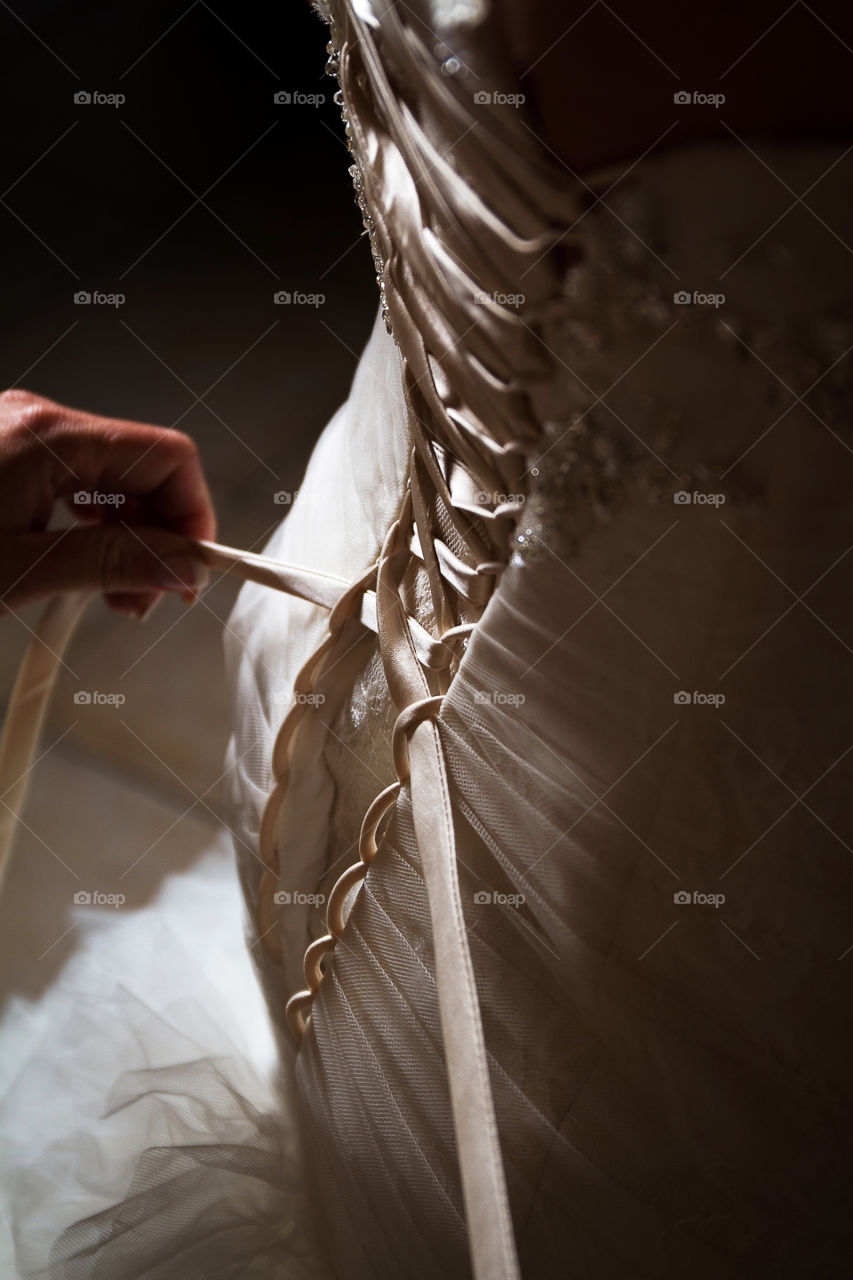 Love the light and shadows in this image of a bride's dress being done up on her wedding day