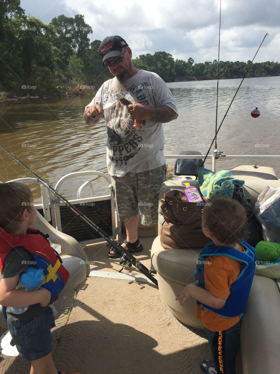 Pawpaw showing the boys how to fish on the boat. They caught a little fish and had to put back in the water. We were at San Jacinto River in Houston Texas 