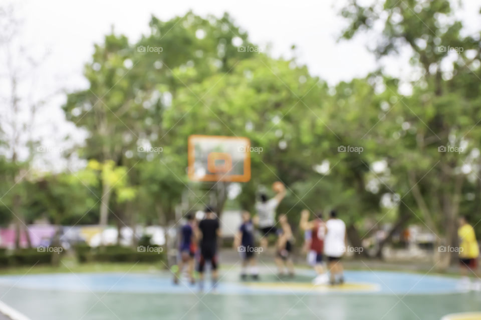 Blurry image of elderly men and teens playing basketball in the morning at BangYai Park , Nonthaburi in Thailand.