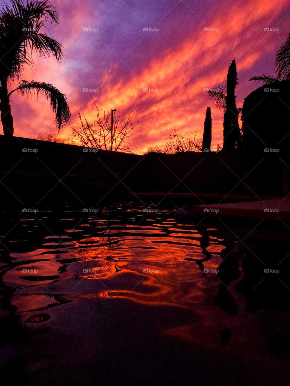 A vibrant Arizona sunset is reflected in the swimming pool