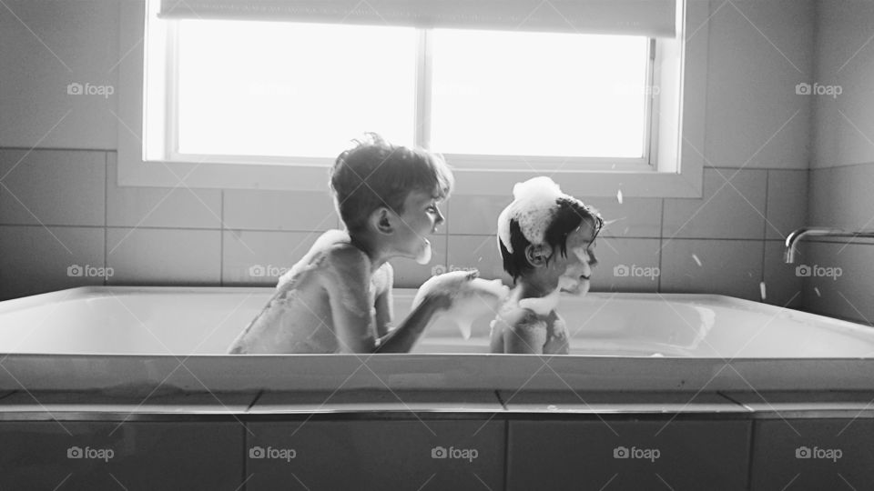 Two boys playing in bathtub