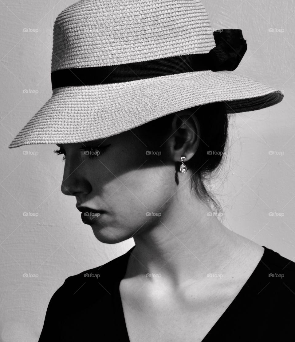 Beautiful young lady wearing at hat that puts a shadow on her face 