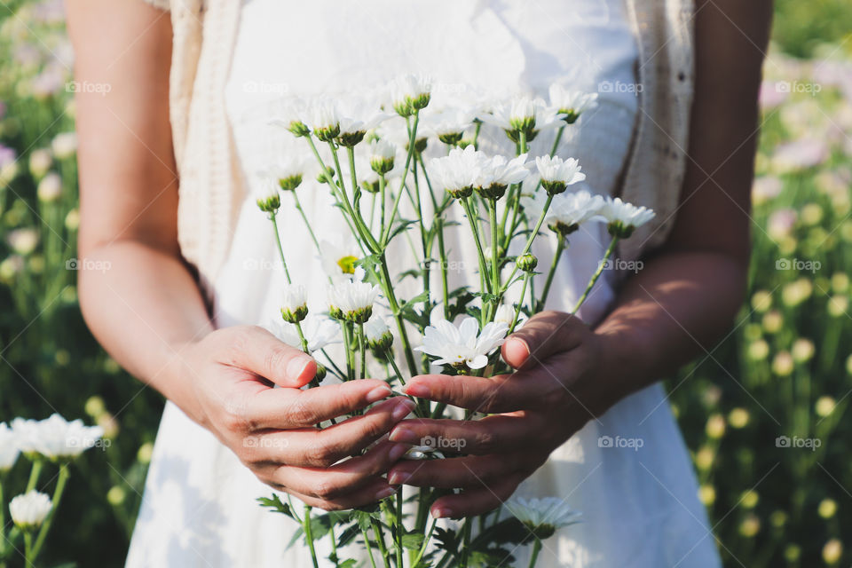 Women standing holding many white flowers in the flower garden