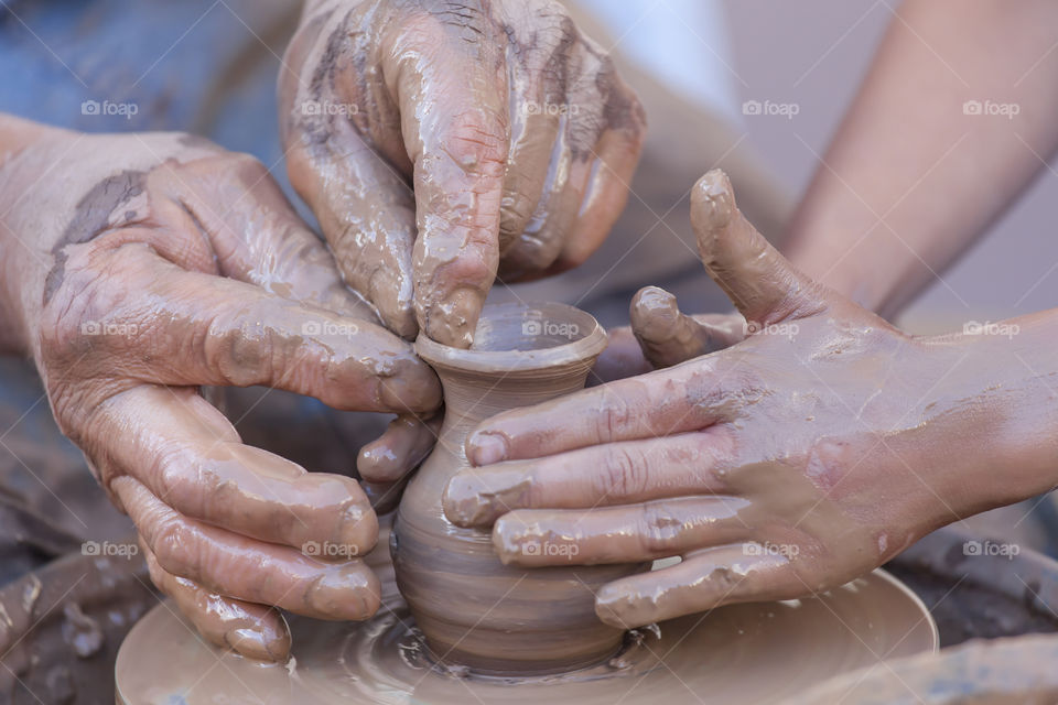 Helping hands at pottery wheel