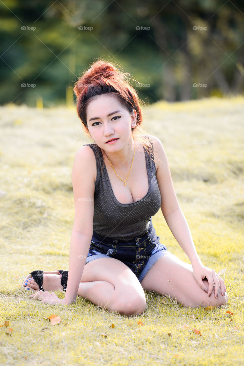 Sexy Asian woman sitting on green grass.