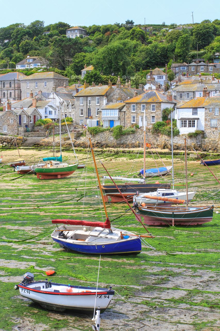 Mousehole harbour in Cornwall at low tide. Fishing boats beached at low tide. A pretty Cornish fishing village.