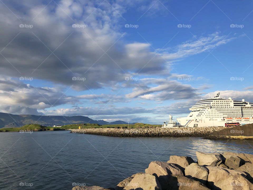 On the shoreline looking at the massive cruise ship at port.  Beautiful-day for those on board to stretch their legs.