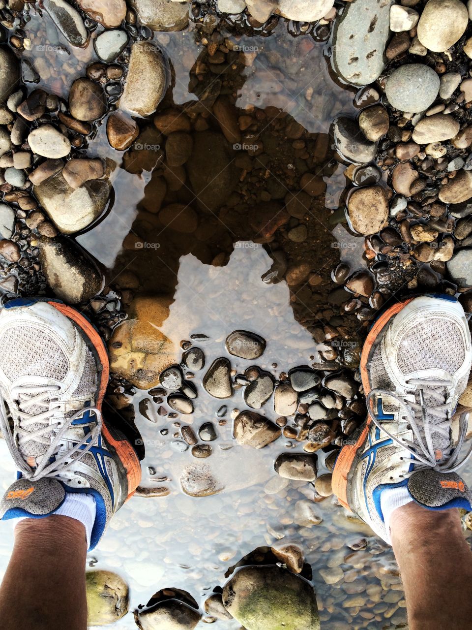 Low section of a man standing on pebble stone