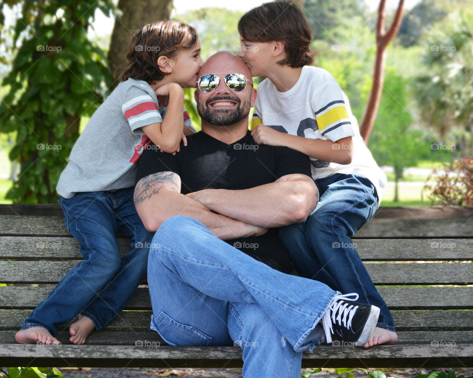 Two boys kissing their father