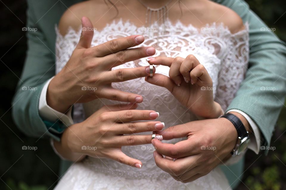 Bride and groom wearing wedding rings to each other 