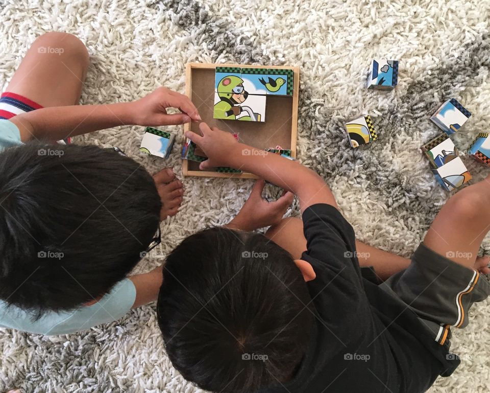 Two brothers working on a block puzzle together.