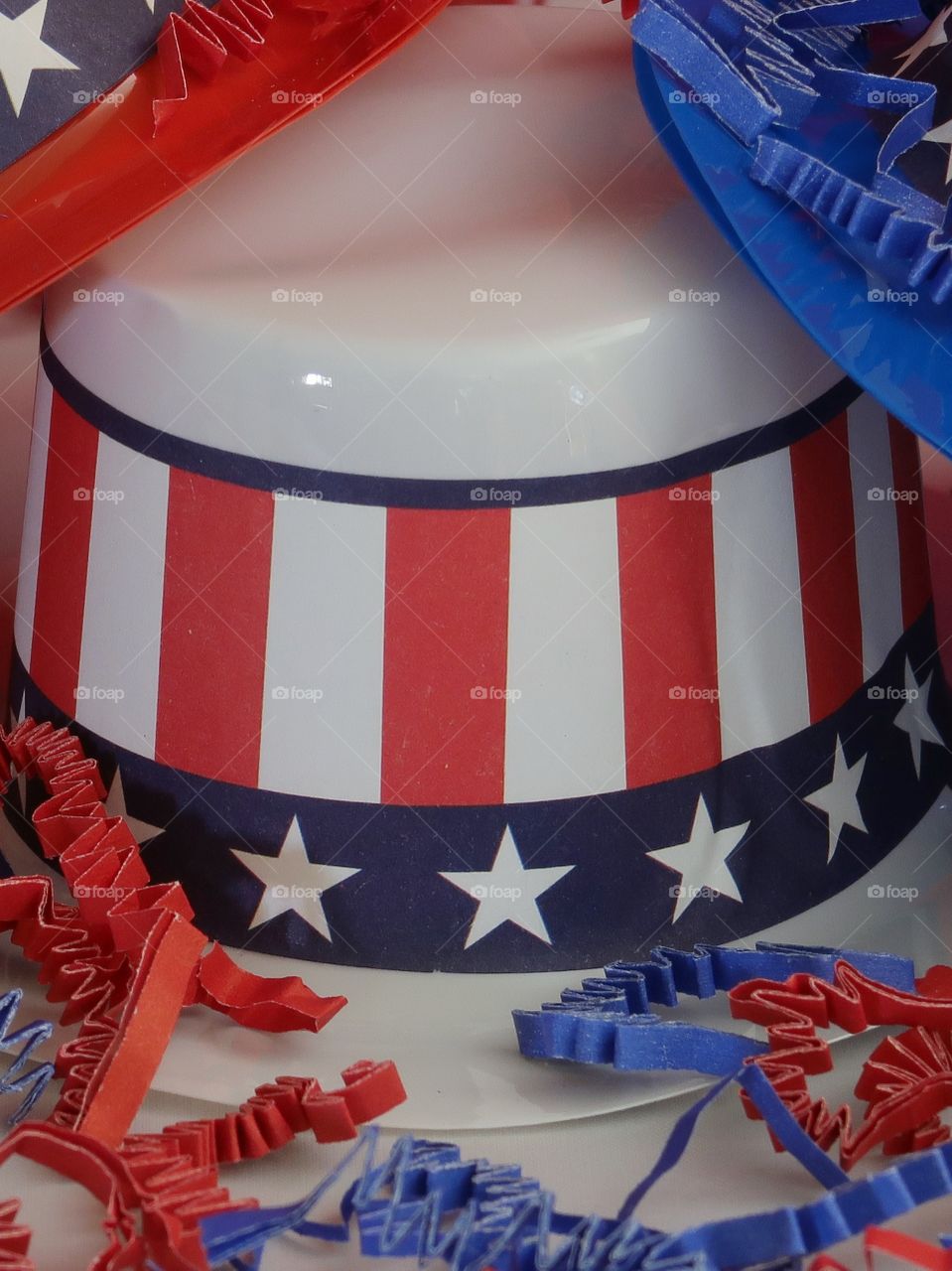 Tiny party hats in red, white, and blue with the Stars and Stripes for hat bands on a table with confetti. 