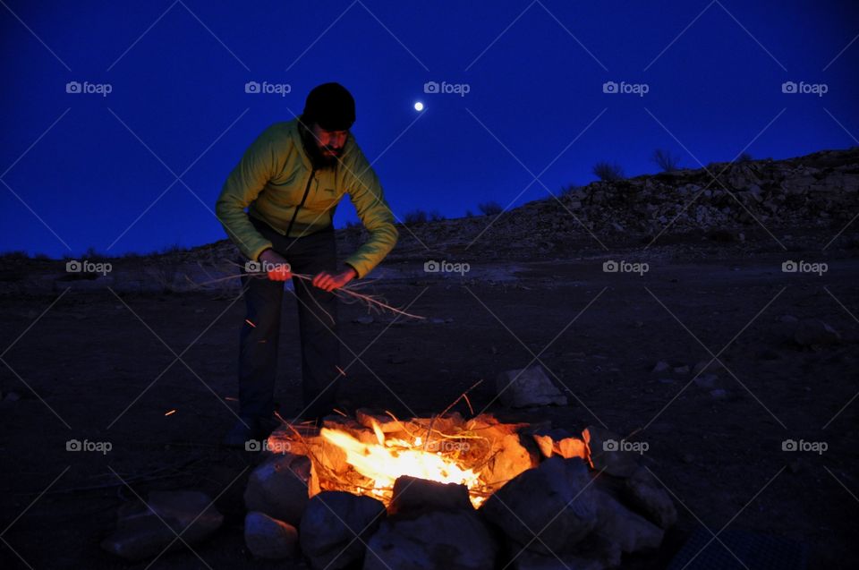 A outdoorsman having a fire on the beach of a rugged Lake Powell. This is a cozy shot of adventure.