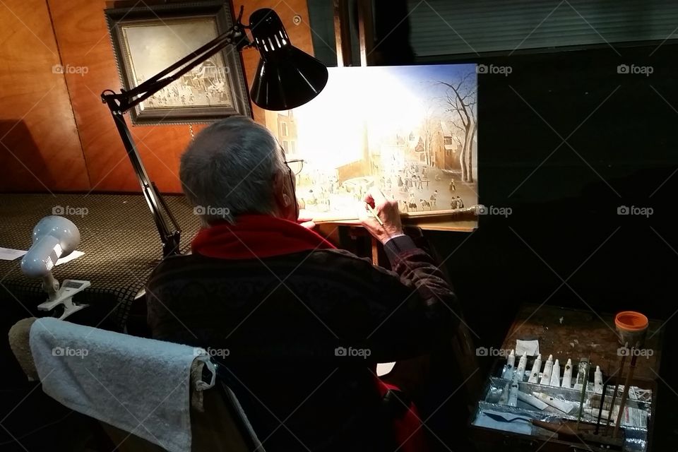 An old painter doing his work at night in Antibes, France