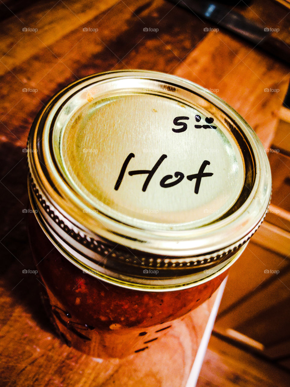 Homemade red chili salsa in a ball jar. Reads "$5 Hot"