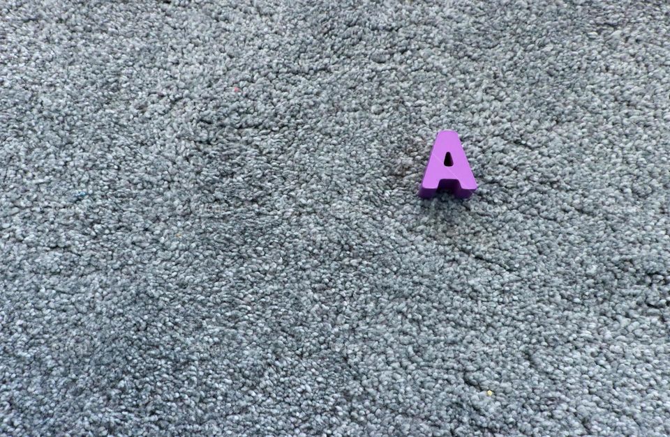 Violet wooden letter A on the gray background