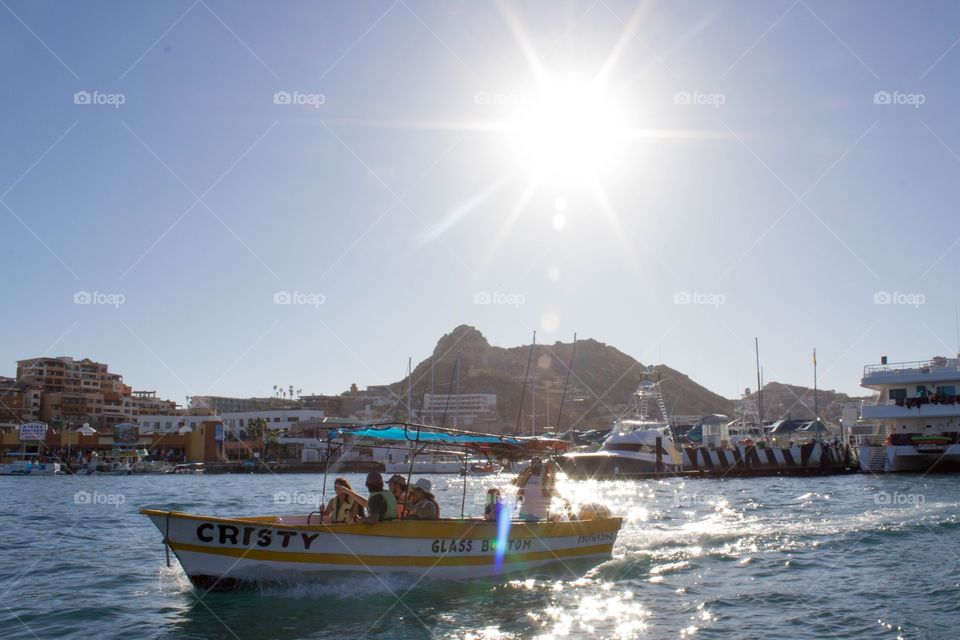 Boat on the ocean with cliffs in the background on a bright, clear sunny day in Cabo San Lucas, Mexico