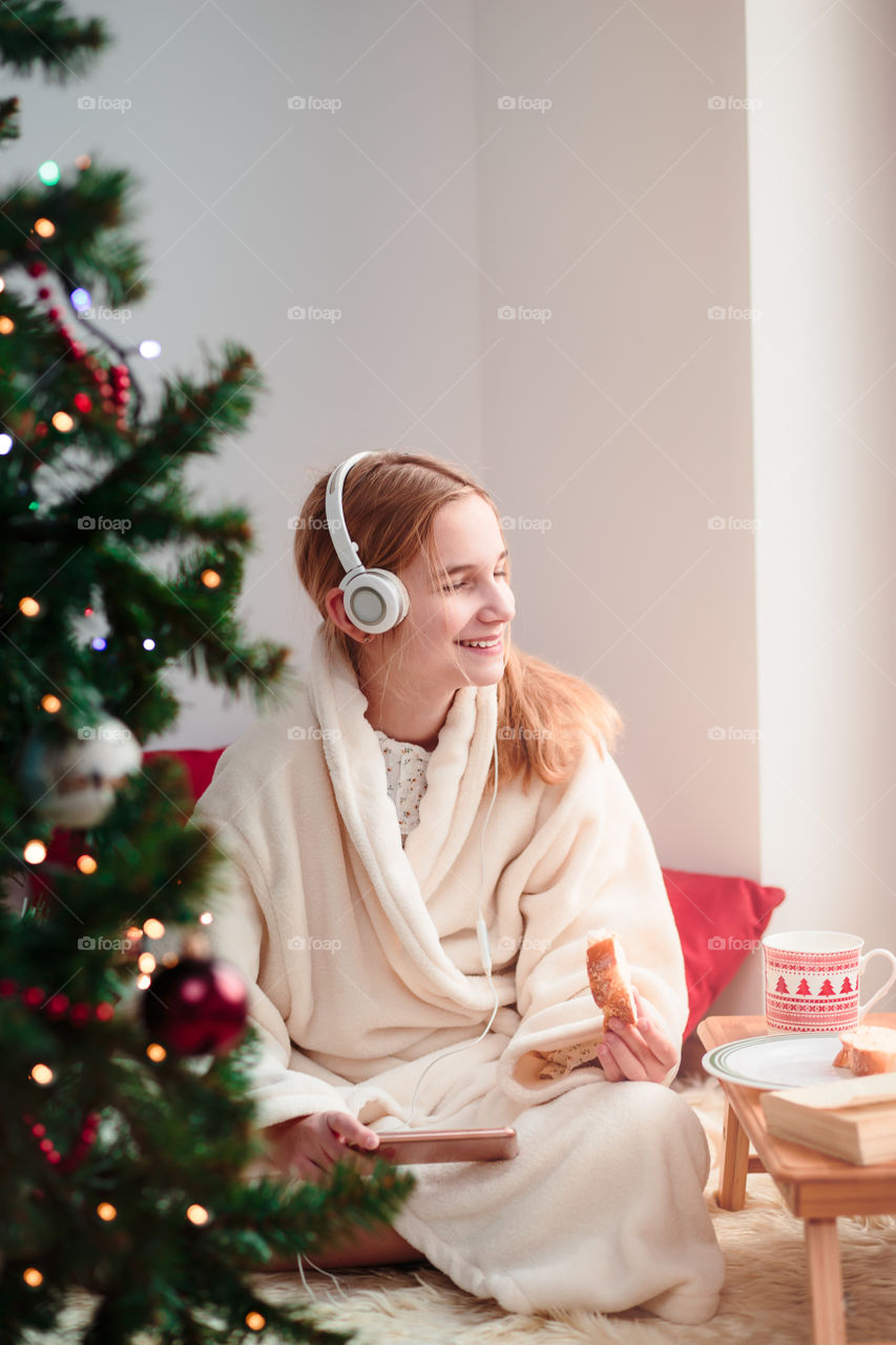 Young girl listening to Christmas carols through her headphones in the early morning