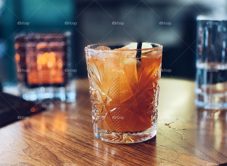 Orange colored drink on tabletop at a fancy bar 