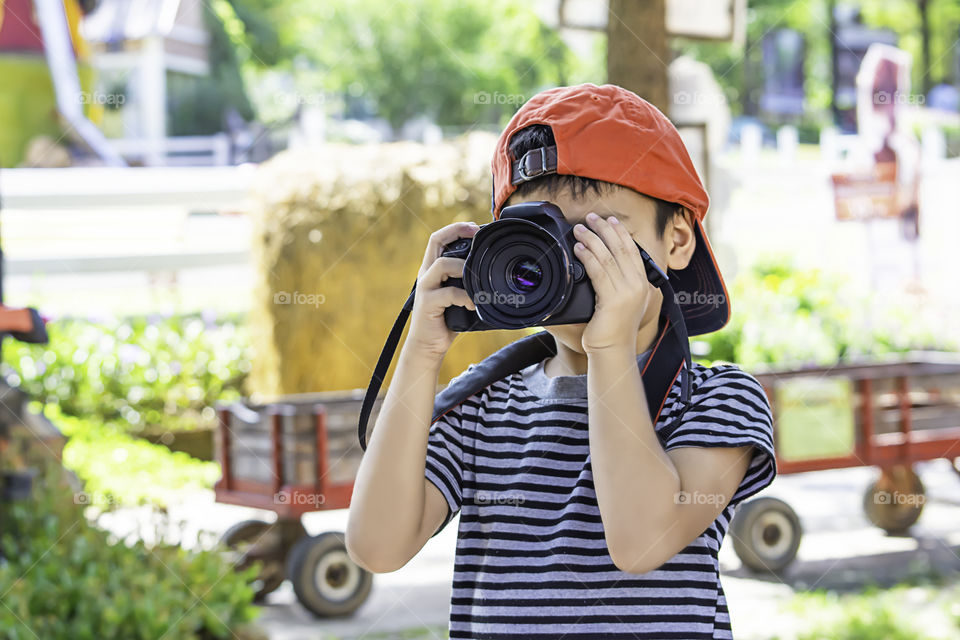 Hand boy holding the camera Taking pictures in park.