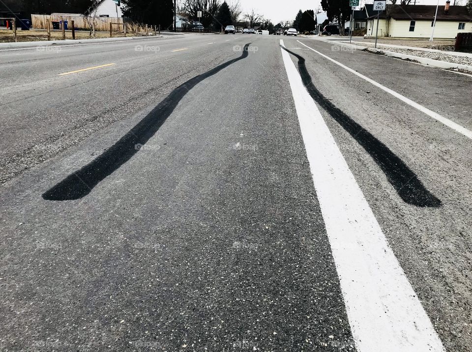 Two black burnouts burned into the asphalt road