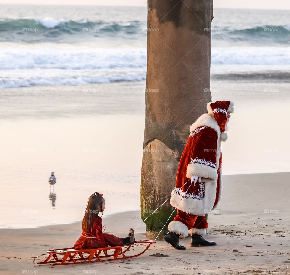 Santa pulling a little girl on a sled.  