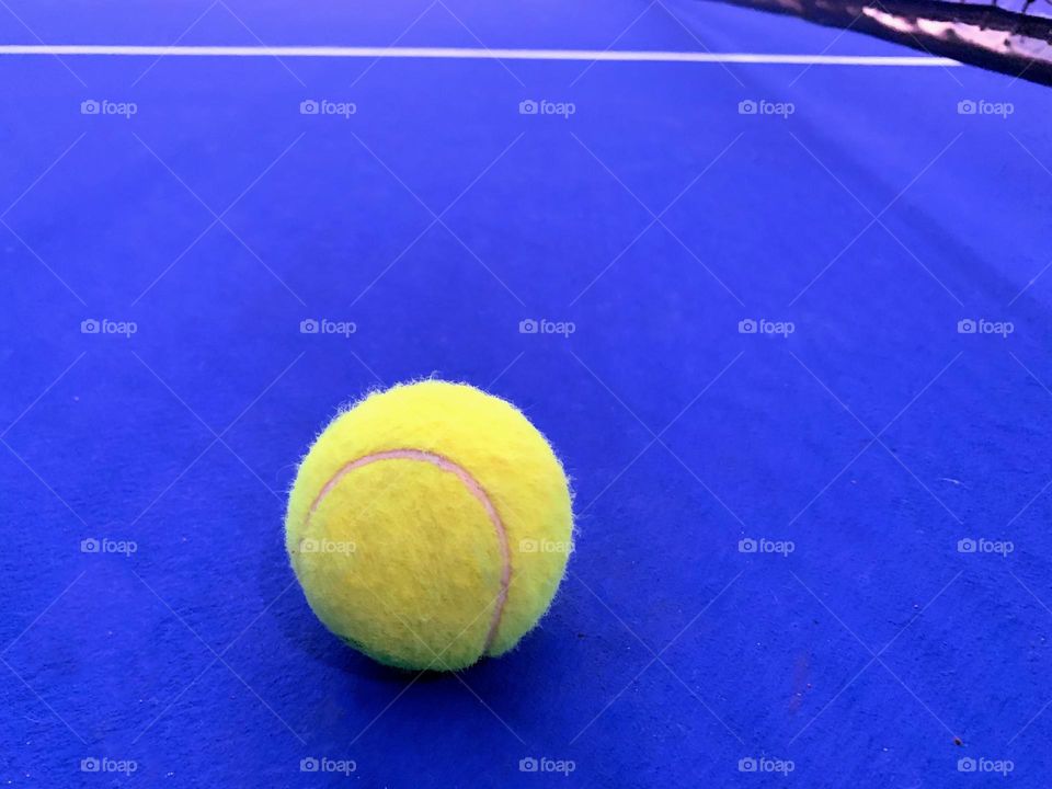 Yellow tennis ball on the blue court