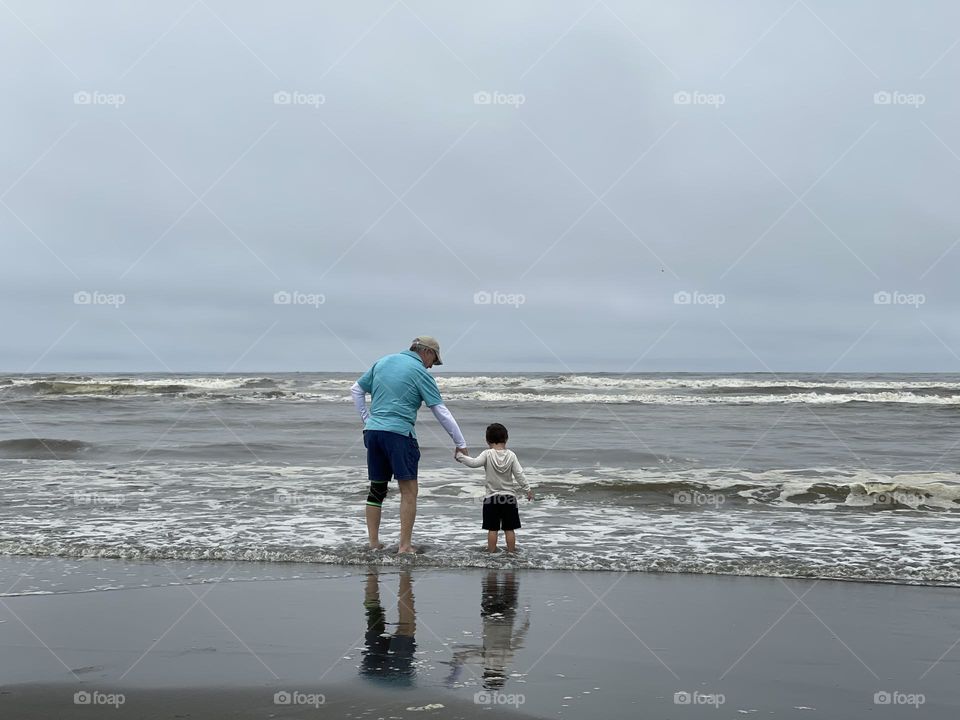 Faceless father and son are walking at the ocean beach 
