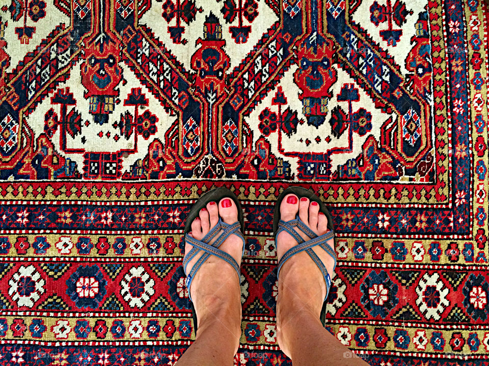 Standing with flip flops on the old Persian carpet. 