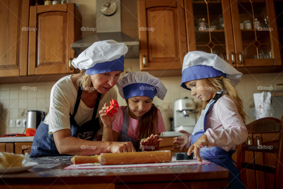 Little sisters with grandma cooking the biscuits 