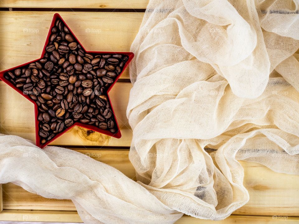 Coffee beans in a red star, on a cheese cloth and wood box