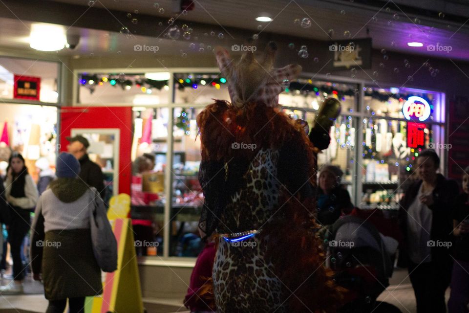 Moonlight Market in my small town is an annual pre- Christmas event on or around a full moon. It’s always an event full of twinkling lights, costumes, fun food & activities. A woman in a fun costume blowing bubbles goes by a busy chocolatier’s shop!