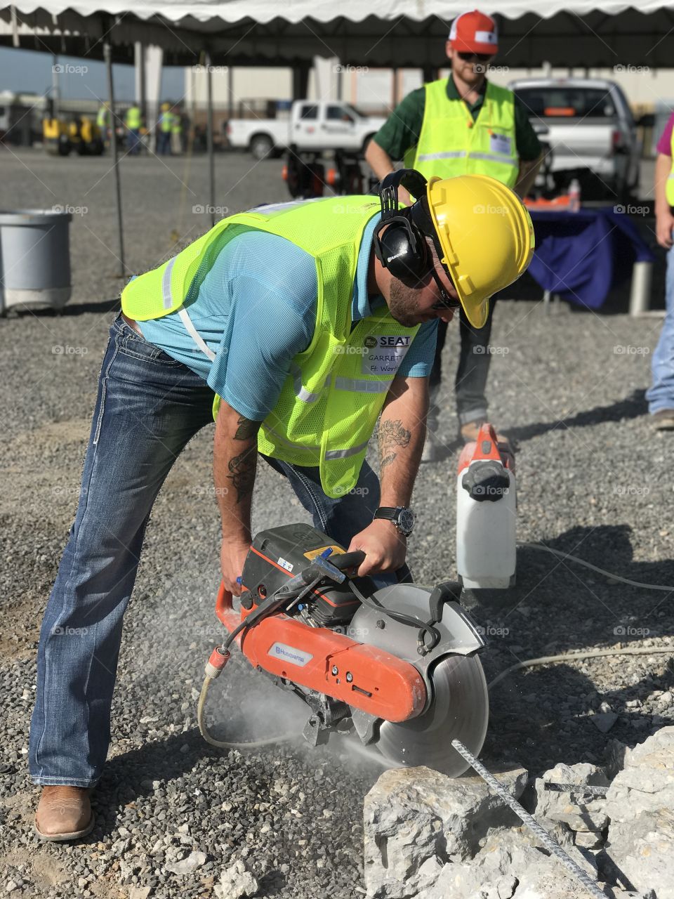 Worker with cut-off machine power tool cutting rock at site
