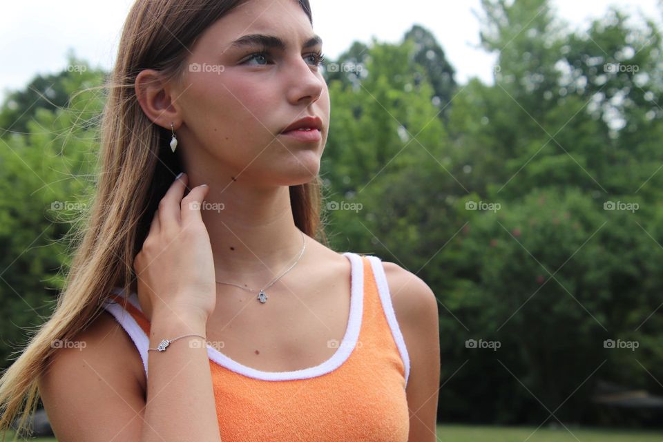 Girl with long brown hair wearing orange tank shirt