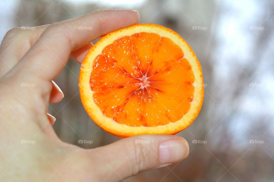 Human hand holding half of orange