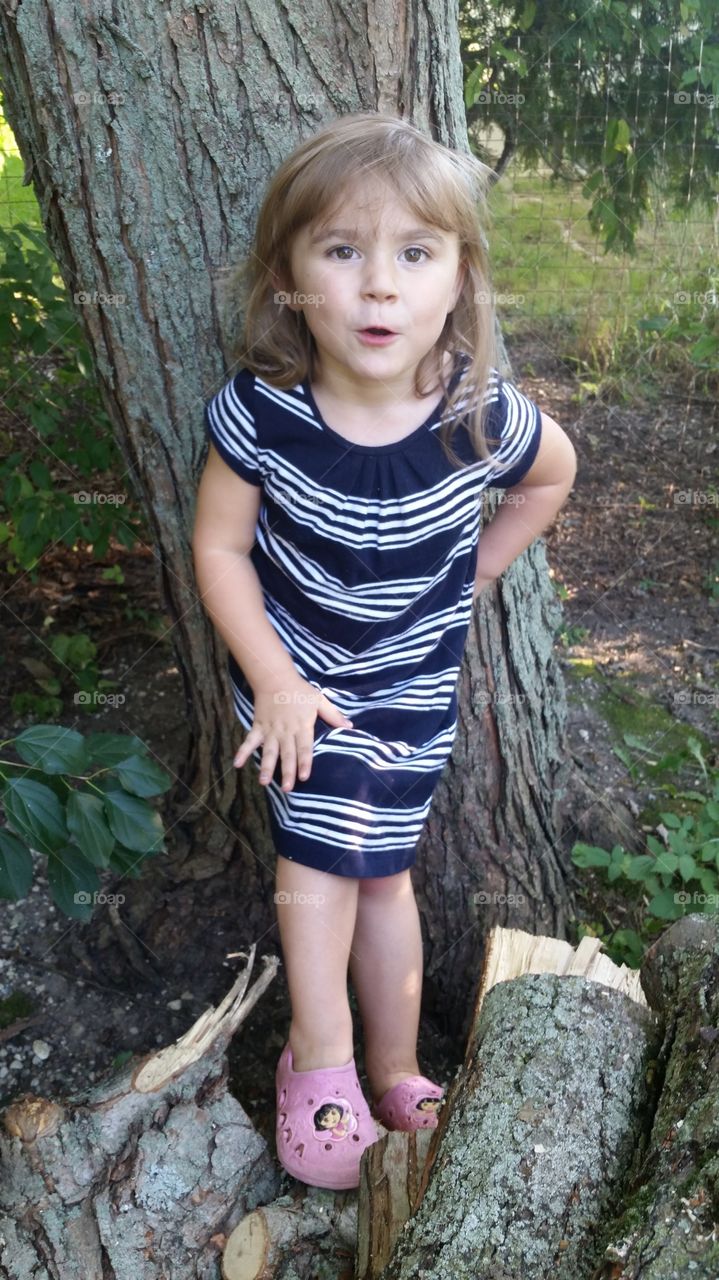 Pretty girl standing near tree trunk
