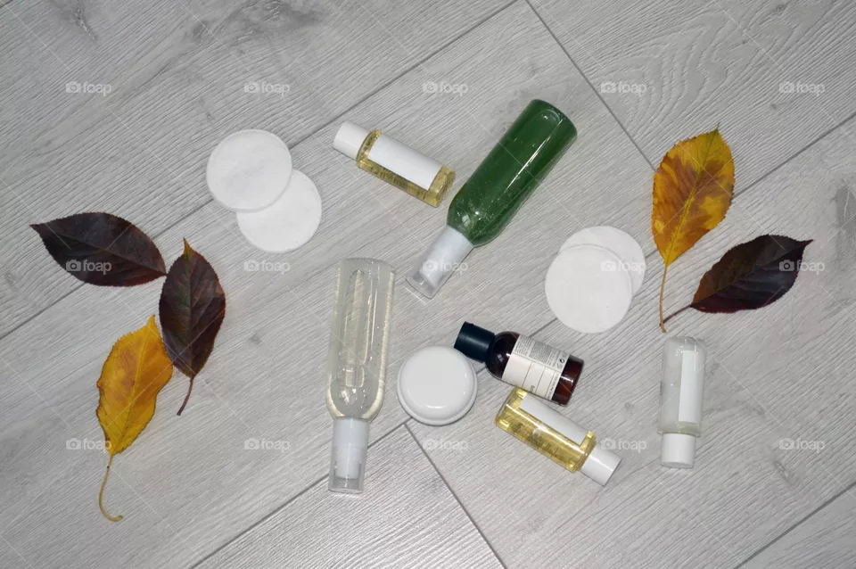 Jars with cream, shampoo and cosmetics on a background with autumn leaves
