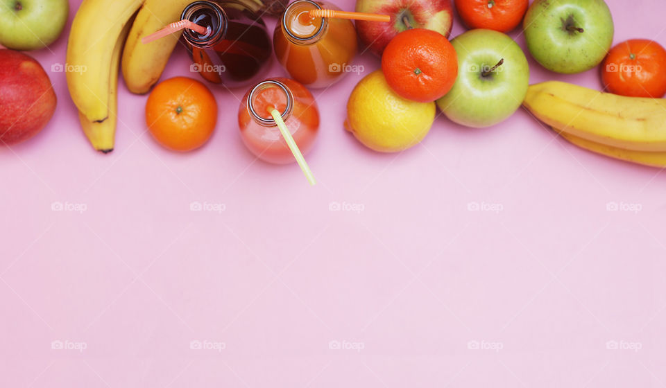 Vitamine health diet fitness concept. Juice bottles and mix fruits. Pink background with copy space. Top view.