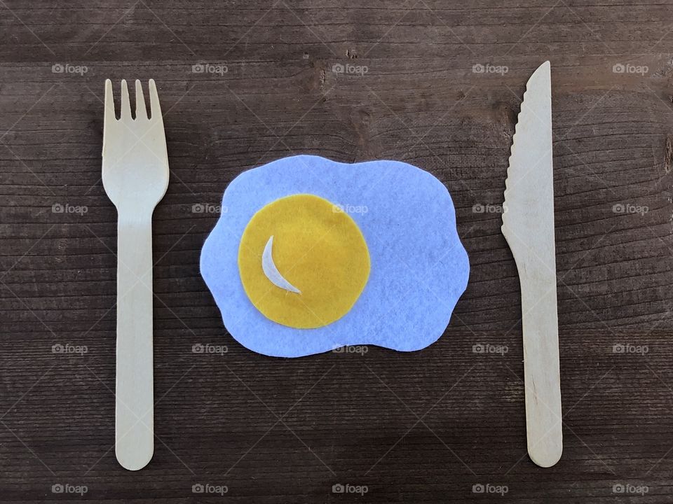 Conceptual artistic composition with a fried egg and wooden cutlery