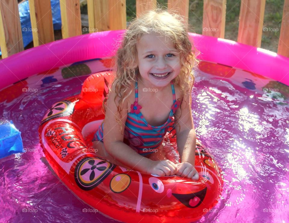 Smiling blonde girl floating on inflatable tub