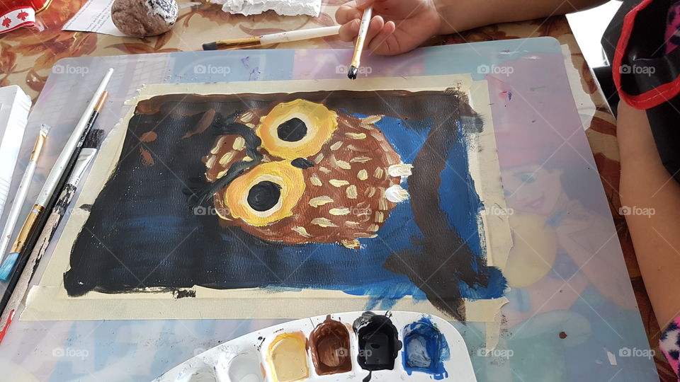 Young child is painting an owl