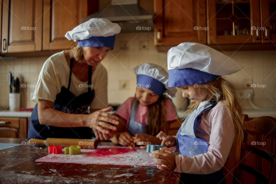 Little sisters with grandma cooking the biscuits 