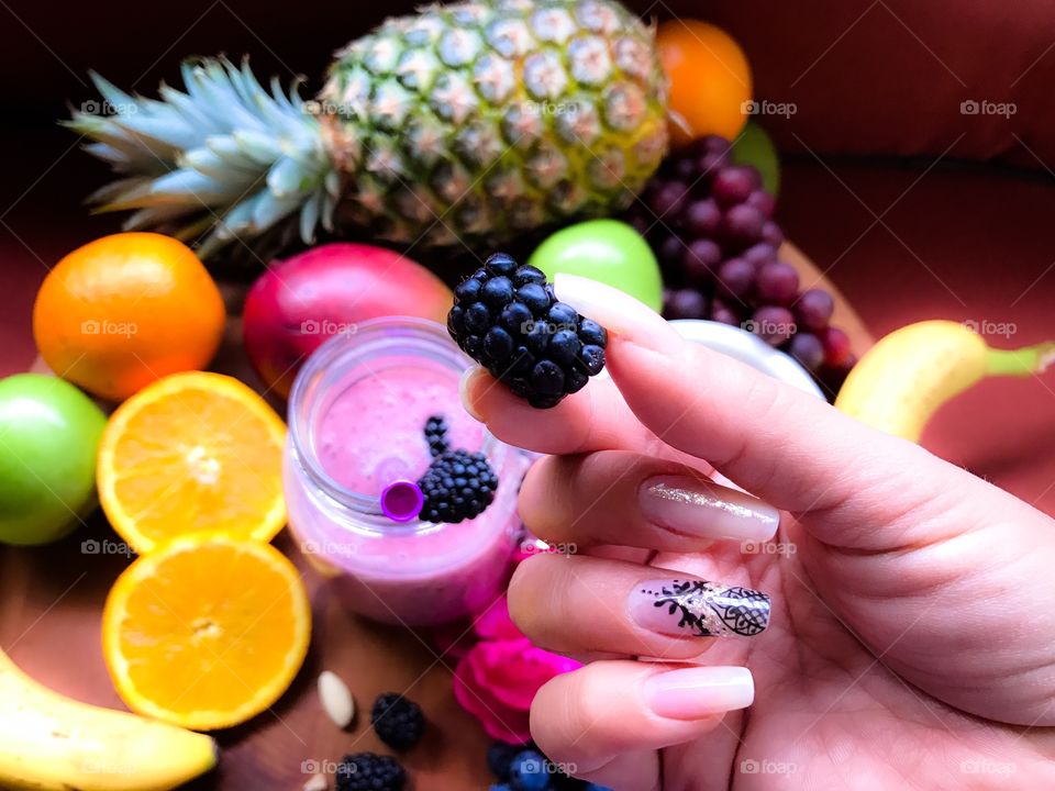 Colorful fruit smoothie with pineapple, berries, oranges, grapes, mangos