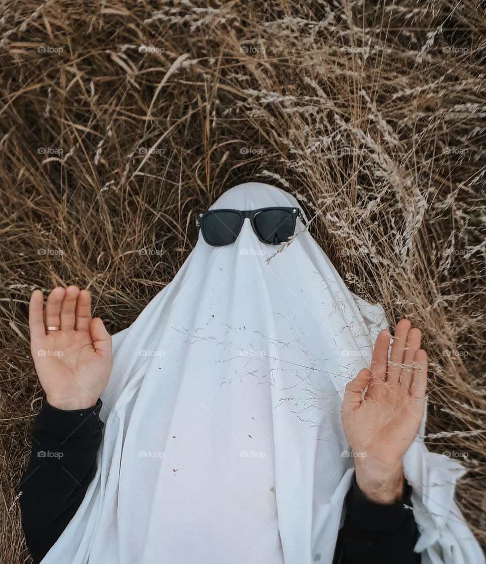 funny photo for Halloween in the form of a ghost in glasses among dry autumn grass