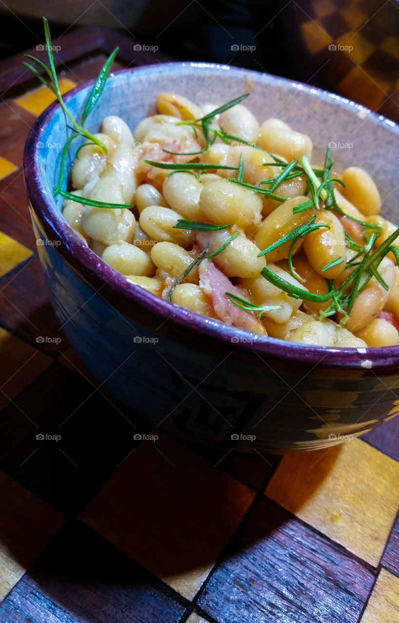 A bowl of beans with pork and herbs