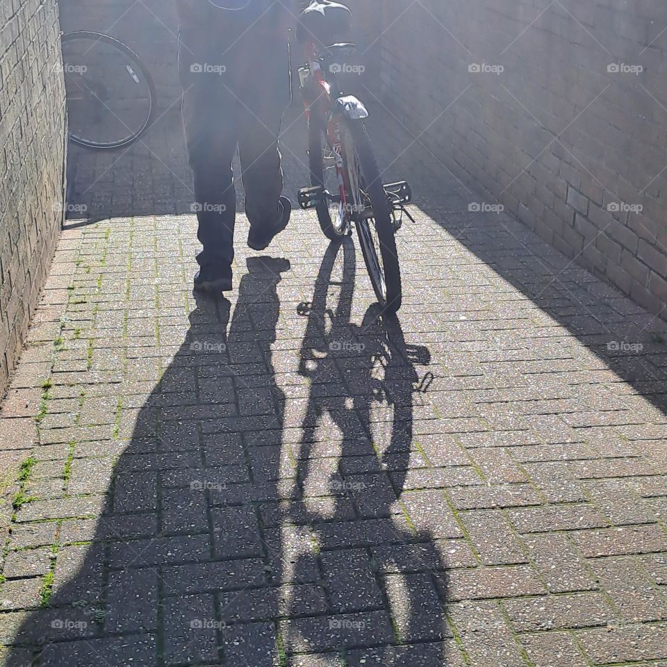 bike riders legs and feet and their shadoes on a sinny floor